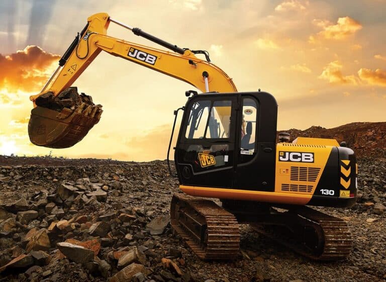 JCB 130 tracked excavator working on broken rock at sunset