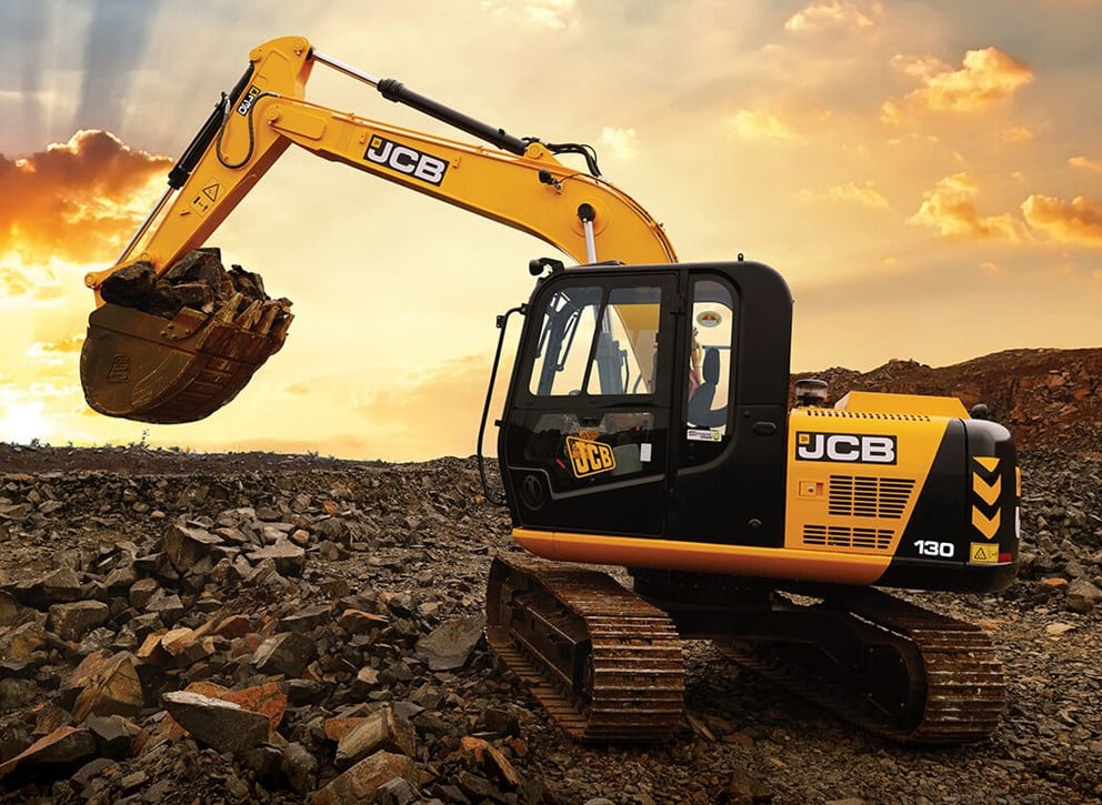 JCB 130 tracked excavator working on broken rock at sunset