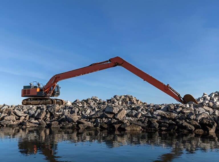 Long-reach excavator working beside water on a canal embankment