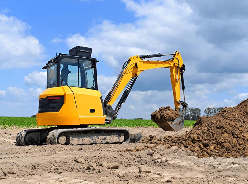 mini excavator removing dirt from farming field.