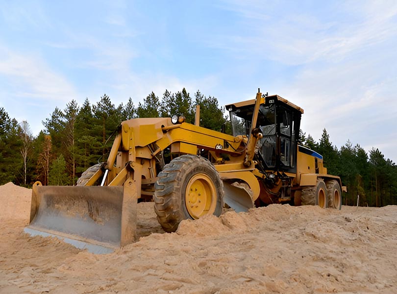 Motor grader grading land